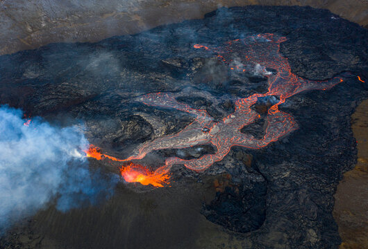 From above magma sparks out of the volcano hole and run like rivers of lava over the ground in Iceland