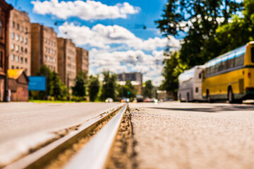 Obraz premium Summer in the city, the street with tramway rails and parked buses. Close up view of a tram rail level
