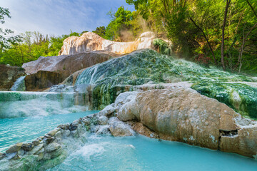 Naklejka premium Geothermal pool and hot spring in Tuscany, Italy. Bagni San Filippo natural thermal waterfall in the morning with no people. The White Whale amidst forest.