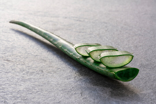 Piece and leaf of green aloe vera placed on gray background in studio