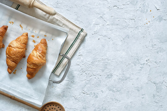 Top view of yummy fresh croissants placed on metal tray on table in kitchen