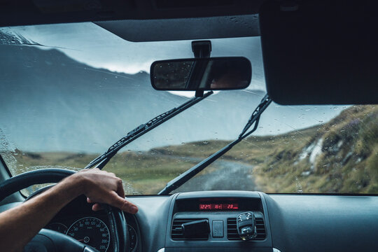 Crop anonymous male driving vehicle on route in majestic Pyrenees mountains during rain