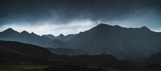 Landscape of Aran valley with majestic green hills and dark gray gloomy sky above