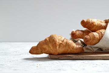 Freshly baked croissants served on wooden cutting board with napkin on table for breakfast