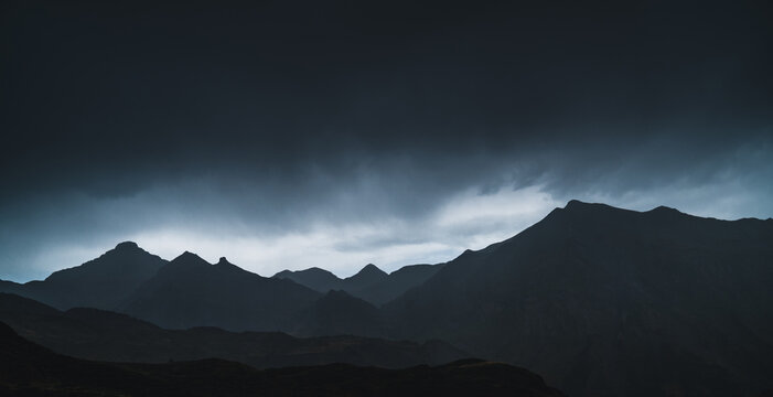 Landscape of Aran valley with majestic green hills and dark gray gloomy sky above
