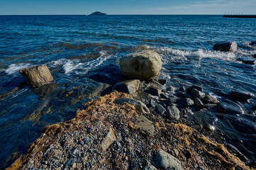 rocky coast of the black sea against the backdrop of a yacht in the sea