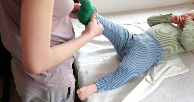 Mom dresses a crying little boy on the bed. Medicine, healthcare, family, innocence, pediatrics, happiness, infant concepts