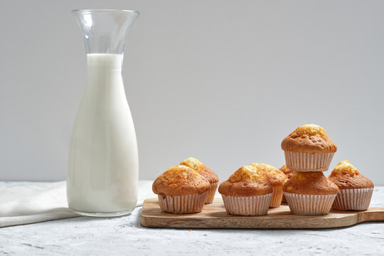 Yummy homemade freshly baked sweet muffins in paper cups arranged on table with glass jar of fresh milk