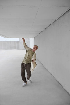 Talented male dancer breakdancing in spacious passage in urban area