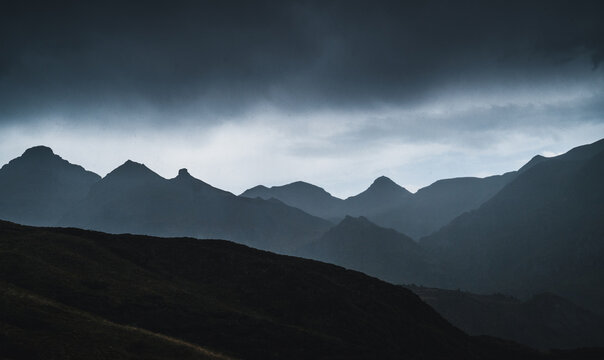 Landscape of Aran valley with majestic green hills and dark gray gloomy sky above