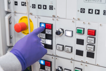 Crop unrecognizable professional male laboratory assistant in white robe and latex gloves pressing buttons on modern equipment