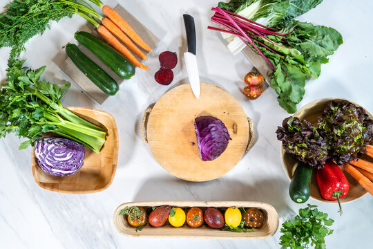 Top view of chopping board with knife and red cabbage among whole and cut vegetables