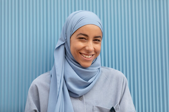 Young lonely Muslim female with melancholic gaze looking at camera against ribbed wall in daytime