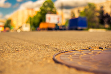 Obraz premium Summer in the city, the cars passing by on the street. Close up view of a hatch at the level of the asphalt