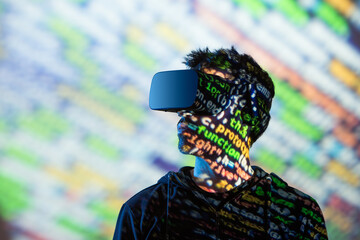 Unrecognizable bearded male in hoodie and modern headset exploring virtual reality in neon light