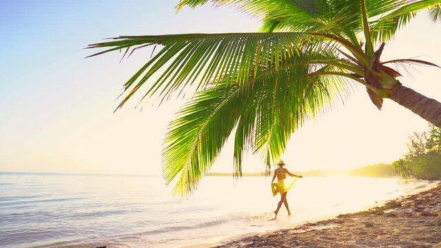 Sunrise over tropical island beach and palm trees. Punta Cana, Dominican Republic. Walking girl on the sand.