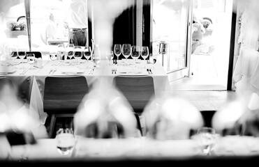 Restaurant with open doors with white blankets with glasses of wine and fully served. Shot through glasses for abstract view.