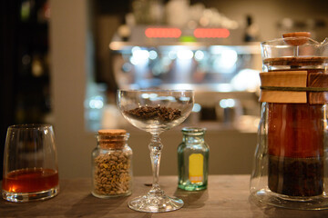 Ground coffee in glass with unroasted coffee beans in background. French press coffee in background.