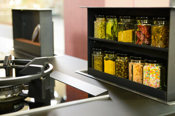 Extendable shelf for spices with various spices in jars in kitchen near gas burner