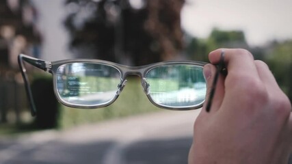 Person holds augmented reality smart tech glasses in hand, futuristic HUD shows code elements in lens. Modern eyewear innovation with IOT and VR. 
