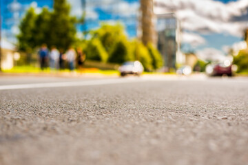 In the downtown, the street with parked cars and pedestrians. Close up view from the asphalt level