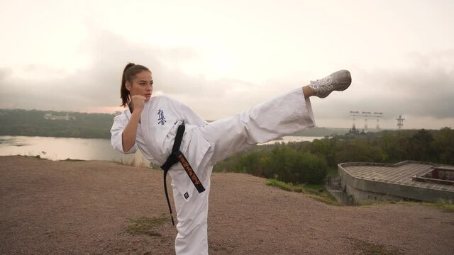 Translation: Kyokushinkai. young beautiful girl karate does handstand on one leg on nature on background river ,forest
