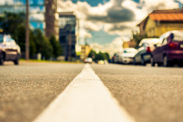 In the downtown, the street with parked cars. Close up view from the level of the dividing line