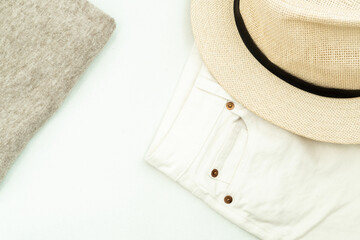 summer flat lay: a gray sweater, white jeans and a woman's hat