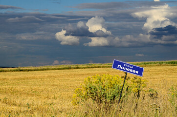 Summer landscape with cumulus clouds over field. Sky, countryside background. Blue nameboard , nameplate.