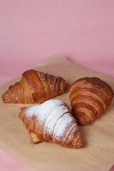 fresh croissants with powdered sugar on the table close-up, blurred background, bread on craft paper