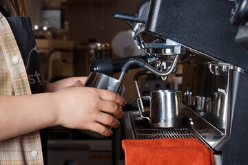 barista prepares and pours coffee into a mug on the coffee machine, close-up, hands of a woman, blurred background
