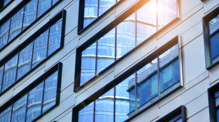 Modern architecture with sun ray. Glass and steel facade on a bright sunny day with sunbeams on the blue sky. Economy, finances, business activity concept.