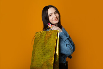 beautiful cute woman with purchases on yellow background 