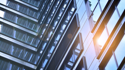 Modern architecture with sun ray. Glass and steel facade on a bright sunny day with sunbeams on the blue sky. Economy, finances, business activity concept.