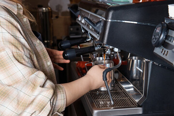 barista prepares and pours coffee into a mug on the coffee machine, close-up, hands of a woman, blurred background
