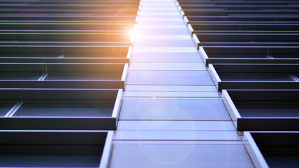 Modern architecture with sun ray. Glass and steel facade on a bright sunny day with sunbeams on the blue sky. Economy, finances, business activity concept.