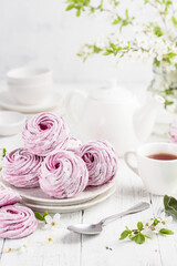 Homemade bilberry zephyr or marshmallows with a cup of tea on a white table. Selective focus