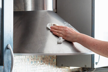 female hand washes stainless steel kitchen hood