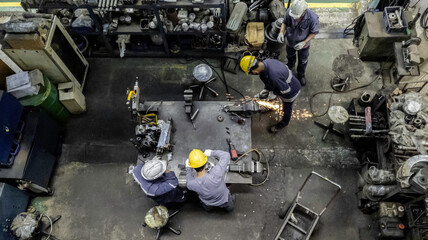 Top view of technician and engineer team work to maintain the machinery part in the industry factory, Machanic serrvice team are cutting and grinding part in the workshop