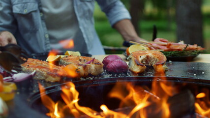 Open fire in bbq grill on backyard. Woman preparing food on grill outdoors.