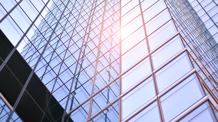 Modern architecture with sun ray. Glass and steel facade on a bright sunny day with sunbeams on the blue sky. Economy, finances, business activity concept.