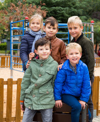 Fototapeta na wymiar Portrait of happy kids standing together on playground in autumn day..