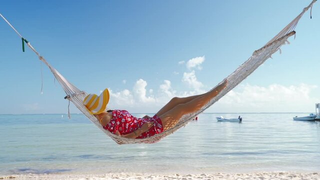 Girl relaxing in a hammock on tropical island beach. Summer vacation in Punta Cana, Dominican Republic