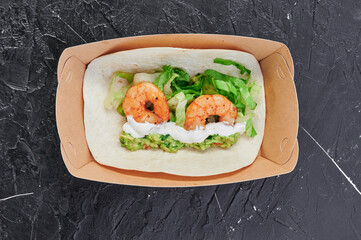 shrimp tacos in a craft container on an isolated dark background. Take away food. Photo for menu and site. Close up. High quality photo