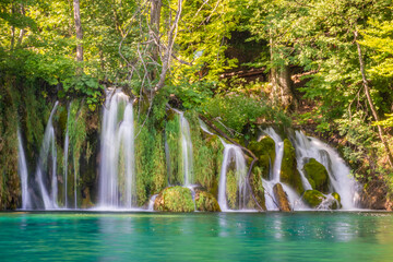 Waterfalls flowing into the crystal water of Lake Plitvice