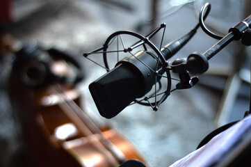 Fototapeta na wymiar Microphone in a recording studio hanging over a cello in the background