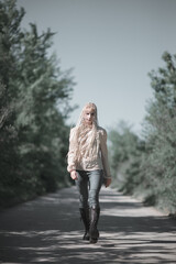 Stylish young woman walking down the forest road, fashion concept