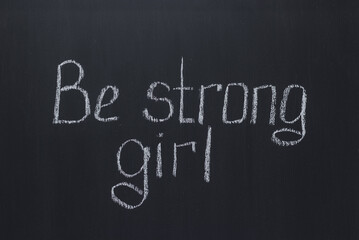 Fototapeta na wymiar Lettering on a dark chalk school board Be strong girl. Motivational lettering