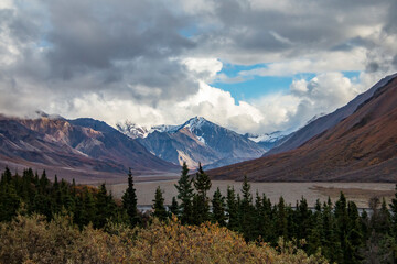 dramatic autumn landscape of snowcapped mountain ranges and peaks inside DEnali National park .