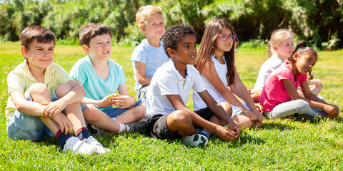 Fototapeta premium Happy team of friends children resting on grass together in park